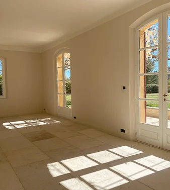 Mur à la chaux beige, réalisé par Altmeyer dans le sud de la France, avec des fenêtres arrondies pour une finition élégante et intemporelle.