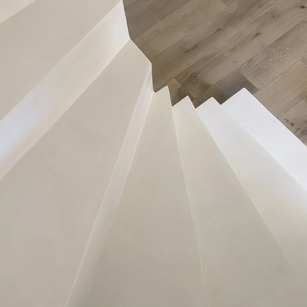 Escalier en béton ciré blanc par Jérémy Altmeyer, avec parquet au sol, une réalisation dans le Var alliant modernité et élégance.
